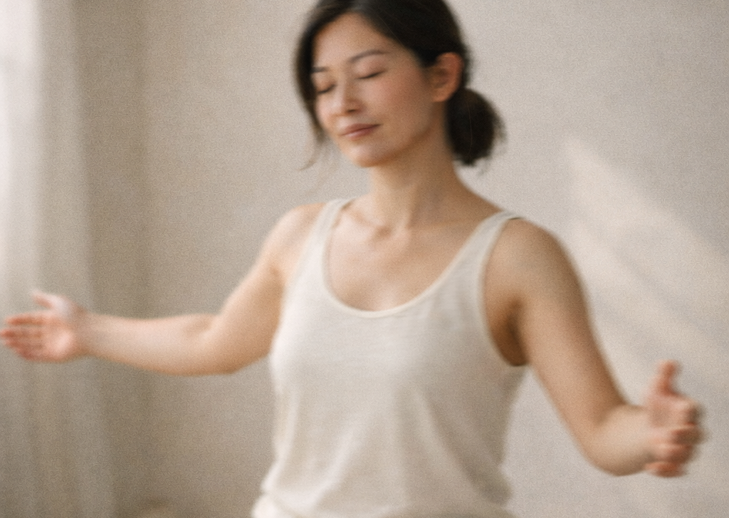 An Asian woman moving slowly in soft natural light, captured mid-motion in a calm, minimal space, symbolizing embodiment and living in alignment.